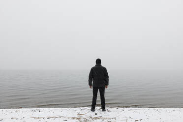 Man standing in snow by lake - FOLF12515