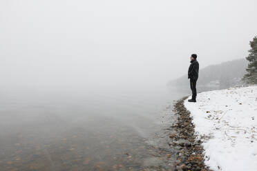 Man standing in snow by lake - FOLF12516