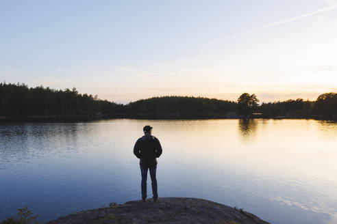 Man standing by lake at sunset - FOLF12520