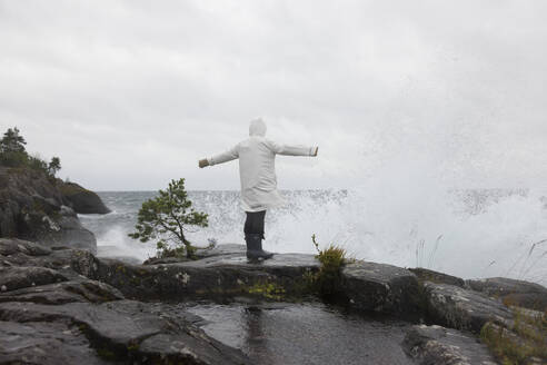 Young woman in raincoat by waves on lake - FOLF12527