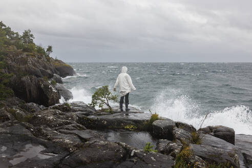 Young woman in raincoat by waves on lake - FOLF12528