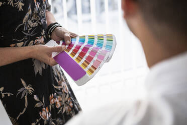 Woman showing paint swatches to colleague in office - FOLF12532