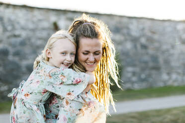 Woman giving her daughter piggyback ride - FOLF12543