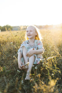 Girl sitting in field during sunset - FOLF12546