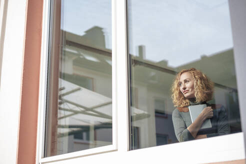 Lächelnde Geschäftsfrau mit Tablet-PC durch ein Fenster gesehen - JOSEF22077