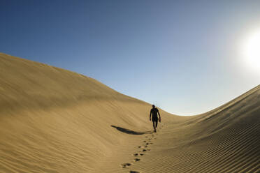 Man walking on sand dunes at sunset - FOLF12618