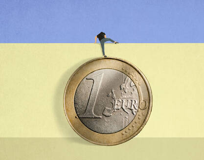 Man standing on oversized Euro coin climbing over wall - GWAF00408