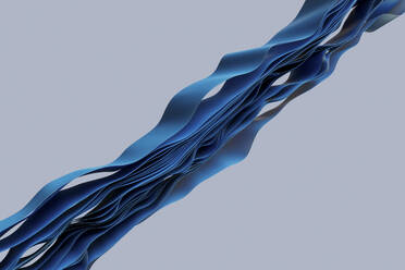 Lagen von blauen Textilien, die in einem Wellenmuster vor grauem Hintergrund fließen - GCAF00484