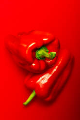 Top view of ripe red peppers placed on top of each other against red background - ADSF49118