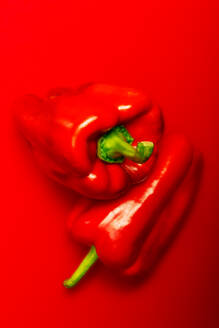 Top view of ripe red peppers placed on top of each other against red background - ADSF49118
