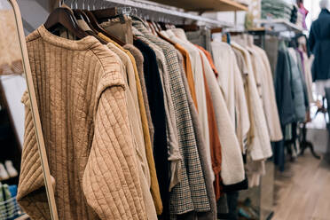 Close-up view of assorted clothes on hangers in a boutique displaying various patterns and textures. - ADSF49154