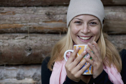 Smiling young woman holding a mug in her hands - FSIF06655