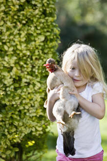 Young girl holding a chicken in her arms - FSIF06658
