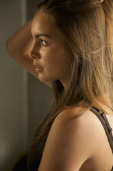 Profile of a young woman pulling hair back - FSIF06668