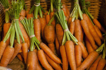 Close up of a basket filled with trimmed bunches of carrots - FSIF06686