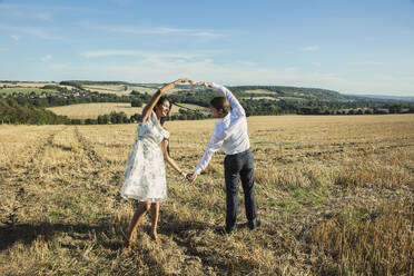 Couple in Field Holding Hands Making Heart Shape - FSIF06727