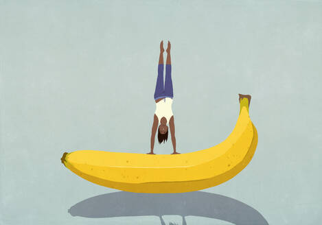 Healthy woman balancing upside-down on banana - FSIF06793