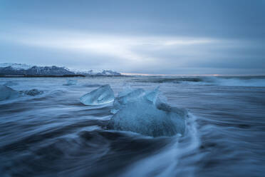 Picturesque scenery of rippling sea water with pieces of broken ice floating against cloudy sky in Diamond Beach in Iceland - ADSF49191