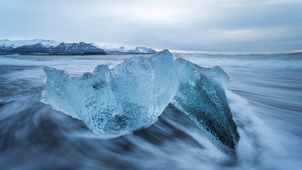 Picturesque scenery of rippling sea water with pieces of broken ice floating against cloudy sky in Diamond Beach in Iceland - ADSF49193