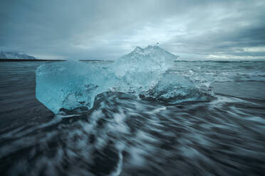 Picturesque scenery of rippling sea water with pieces of broken ice floating against cloudy sky in Diamond Beach in Iceland - ADSF49199