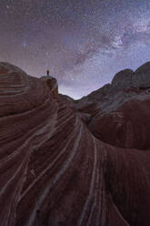 Back view full body of anonymous traveler standing on hill near mountains under starry sky in Utah USA - ADSF49205