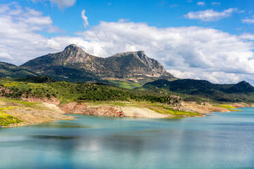 Scenery of green valley with mountains and lake under cloudy sky in Zahara de la Sierra region of Andalusia and water reservoir Spain - ADSF49227