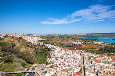 Scenery of village against green valley with mountains and lake under cloudy sky in Zahara de la Sierra in Pueblos Blancos region of Andalusia and water reservoir Spain - ADSF49231