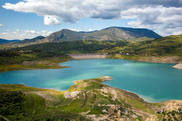 Picturesque view of blue lake with green grass and mountains on cloudy day in countryside against overcast sky over mountain ridge covered by hoarfrost - ADSF49236