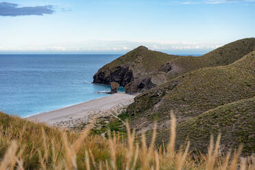 From above a beach next to some mountains under a sky with clouds - ADSF49241