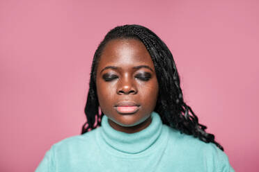 African woman with closed eyes, showcasing subtle makeup, set against a pink background - ADSF49263