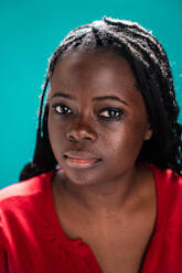 Close-up of an African woman with detailed eyes and braided hair against a turquoise background - ADSF49285