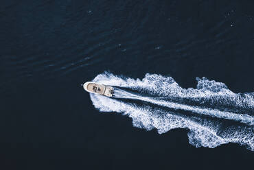 Top drone view of trail on water surface behind fast moving white motorboat floating in sea in El Rompido - ADSF49294