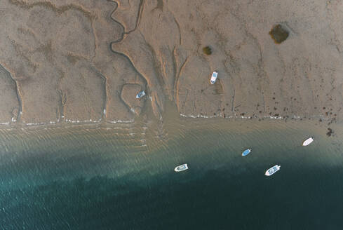 Aerial top view of various boats floating in turquoise ocean near sandy beach on sunny summer day in El Rompido - ADSF49295
