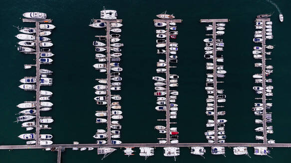 Aerial top view of various types of boats moored in harbor in dark sea water during daytime in El Rompido - ADSF49299