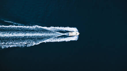 Top drone view of trail on water surface behind fast moving white motorboat floating in sea in El Rompido - ADSF49300