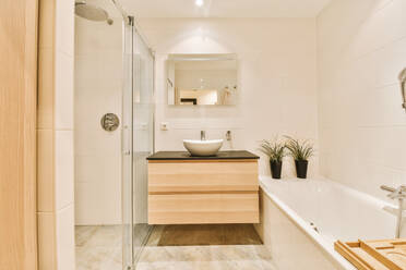 Shower cabin with bathtub and mirror over sink in modern stylish bathroom with white tiled walls at home - ADSF49336
