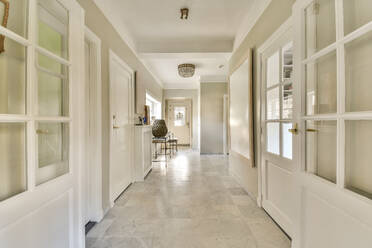 Empty hallway with white closed doors of different rooms and marble floor in modern spacious apartment - ADSF49343