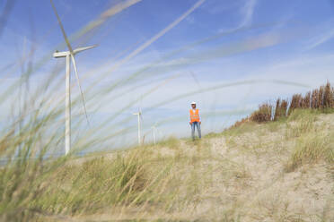 Ingenieur steht in der Nähe von Windkraftanlagen - PHDF00087