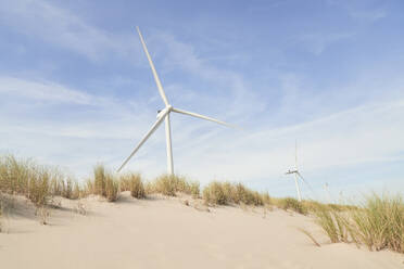Windkraftanlagen auf einer Sanddüne unter bewölktem Himmel - PHDF00095
