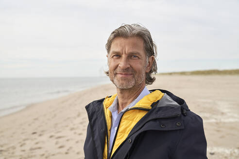 Lächelnder Mann am Strand stehend - PHDF00116