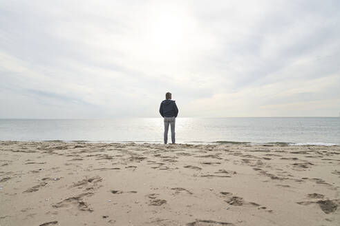 Mann steht vor dem Meer am Strand - PHDF00119
