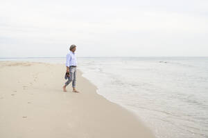 Mann, der an der Küste am Strand spazieren geht - PHDF00135