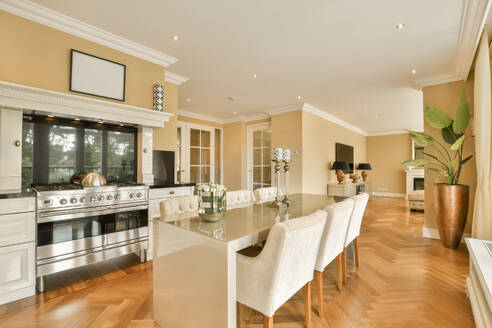 Interior of open plan kitchen with dining table and chairs arranged in modern spacious apartment - ADSF49389