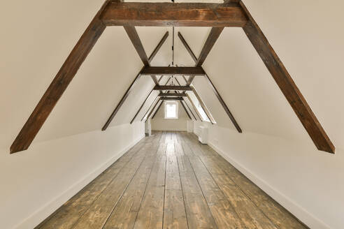 Interior of empty attic room with wooden beams and white walls in contemporary light house - ADSF49395