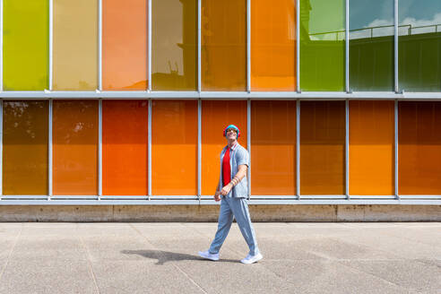 Man walking confidently past a colorful windowed building - ADSF49493