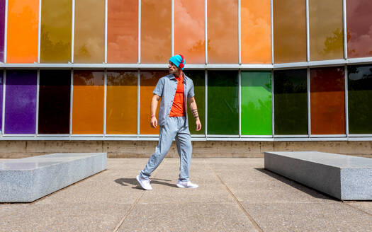 Man walking confidently past a colorful windowed building - ADSF49499