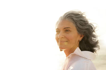 Smiling mature woman with gray hair at beach - AAZF01267