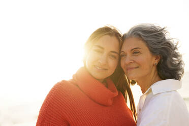 Happy mother and daughter in front of sky on sunny day - AAZF01272