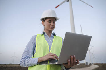 Ingenieur bei der Arbeit an einem Laptop auf dem Gelände einer Windkraftanlage - ALKF00857