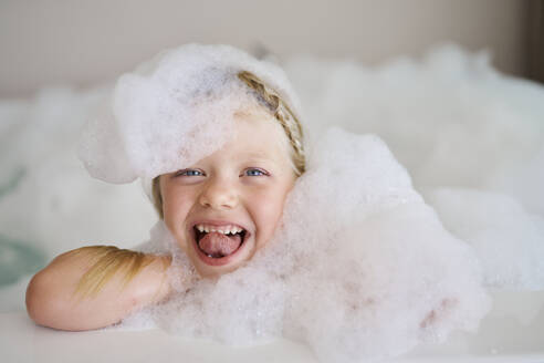 Cheerful girl covered in soap suds and sticking out tongue - ANNF00617